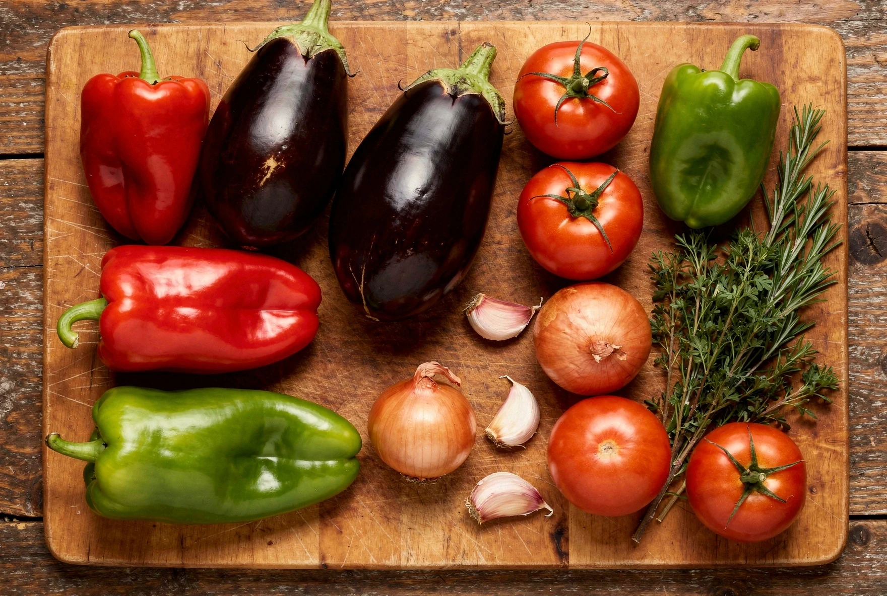 Fresh ajapsandali ingredients: eggplants, tomatoes, peppers, garlic, cilantro, and spices