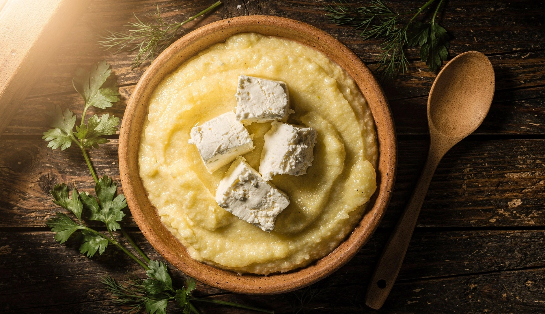 Overhead view of ghomi, Georgian cornmeal porridge topped with melting sulguni cheese in a clay bowl