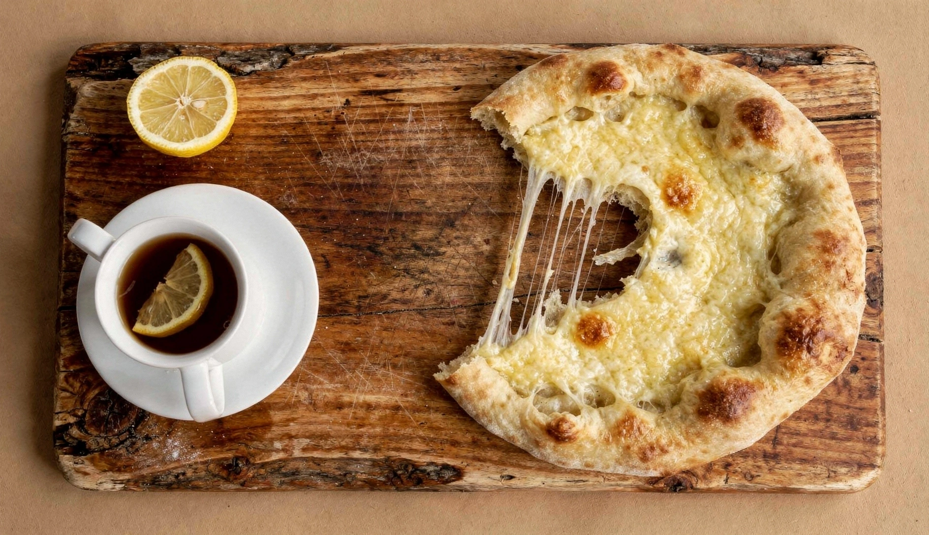 Overhead view of freshly baked Imeretian khachapuri cut into wedges showing melted cheese filling on rustic wooden table