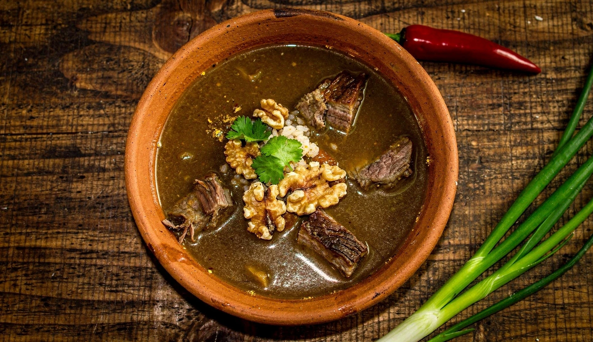 Georgian kharcho beef soup with rice, walnuts and fresh cilantro in a rustic ceramic bowl