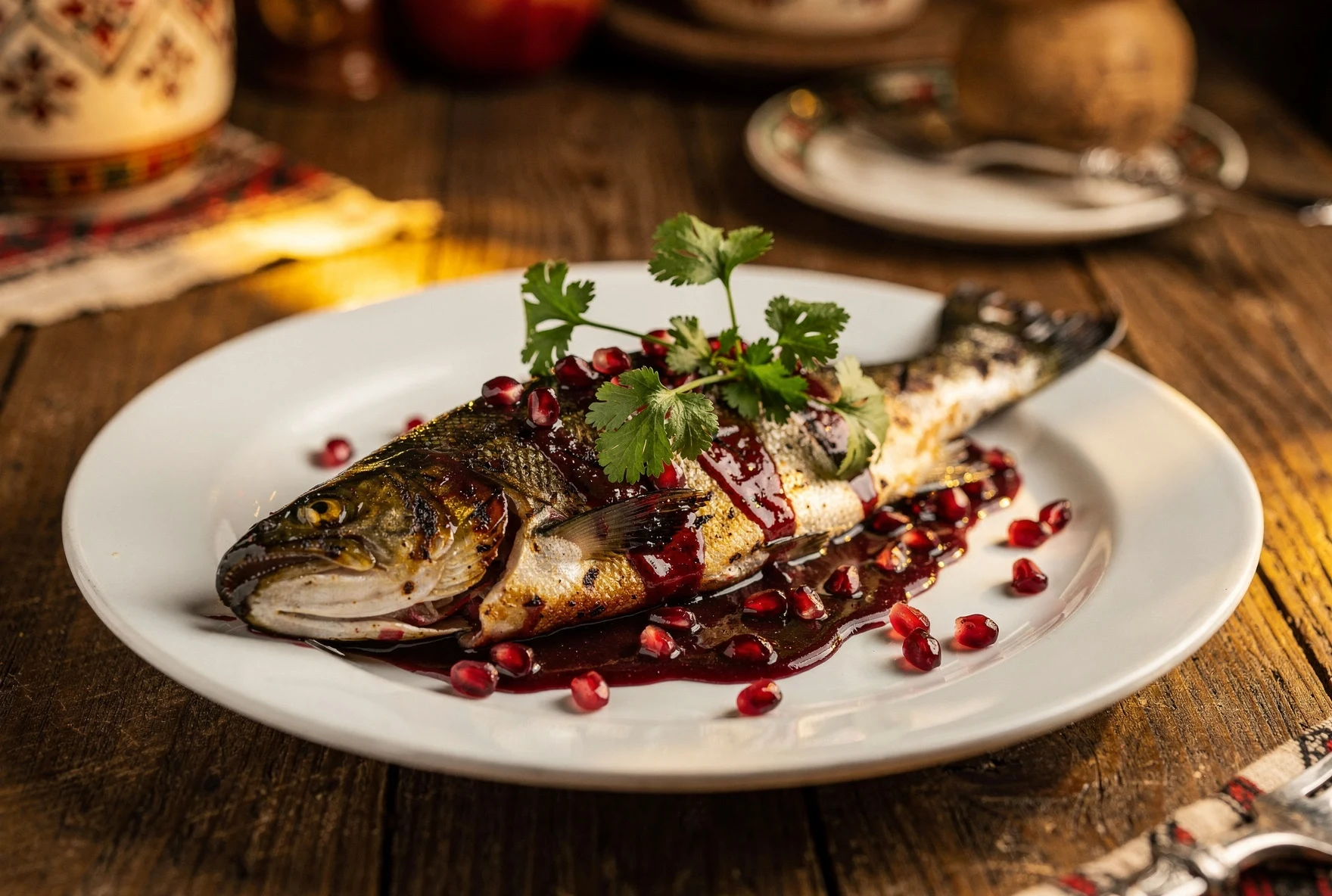 Grilled trout fillet in pomegranate sauce garnished with fresh pomegranate seeds and cilantro