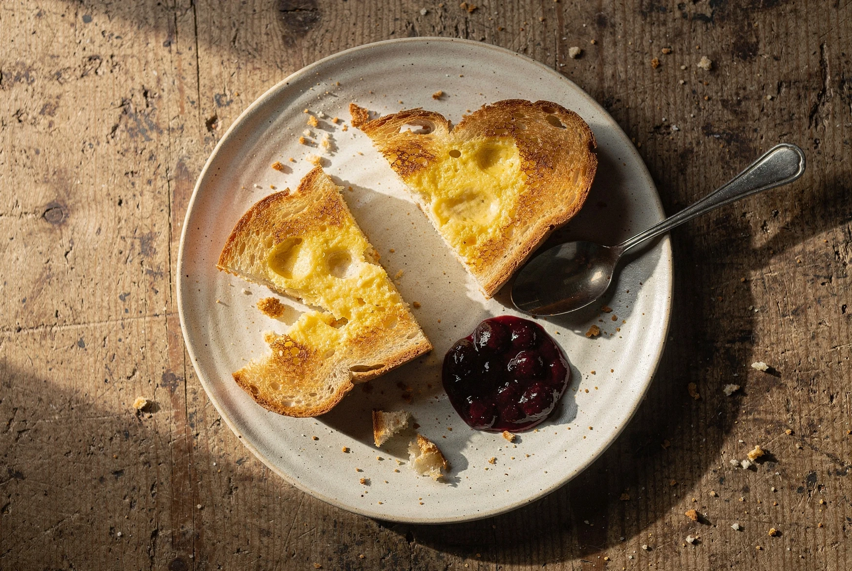Overhead view of Georgian kikliko, golden slices of egg-fried bread served on a rustic plate with sour cherry jam and fresh cheese