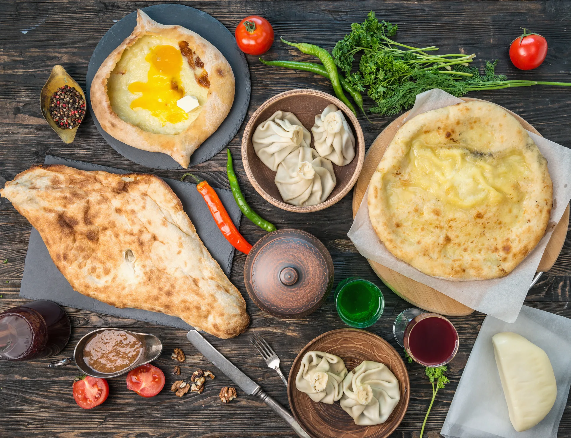 Spread of Georgian dishes including khachapuri, khinkali, and fresh vegetables