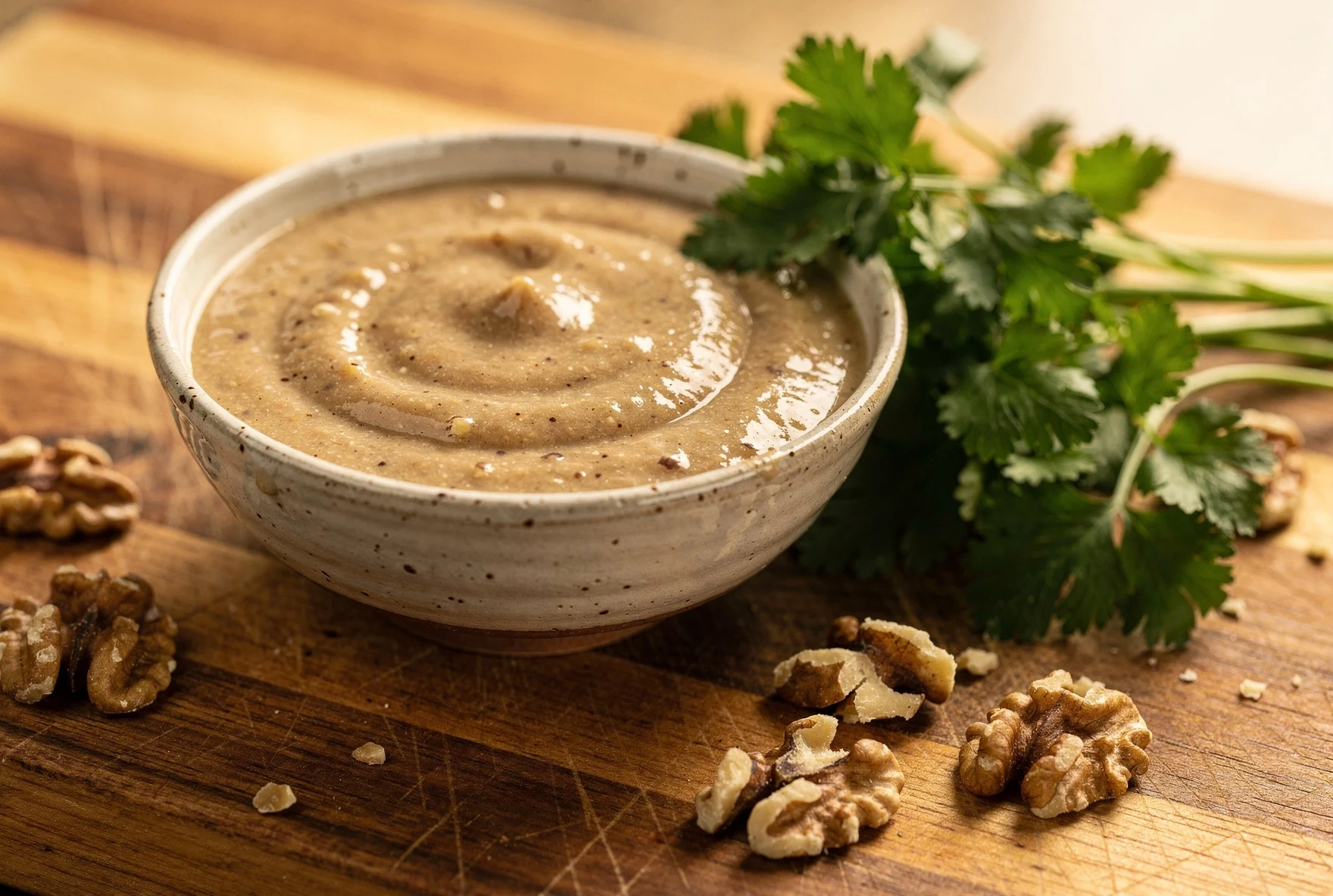 Creamy Georgian walnut dressing in ceramic bowl with walnuts and fresh herbs